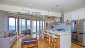 Een moderne keuken met een groot schiereiland, barkrukken en uitzicht op de oceaan.