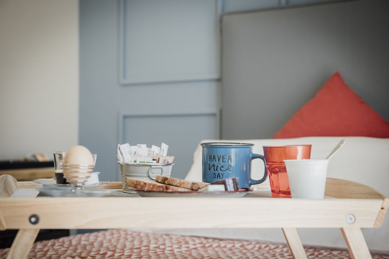 A breakfast tray with a mug, a cup, a bowl of cereal, and a plate of toast on a wooden table.