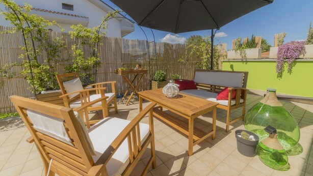 An outdoor patio with wooden furniture, a table, and an umbrella.
