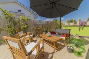 Une terrasse extérieure avec des meubles en bois, une table et un parasol.