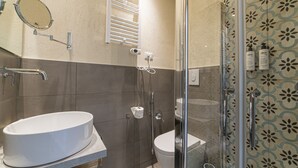 A bathroom with a white sink, a toilet, and a glass-enclosed shower.