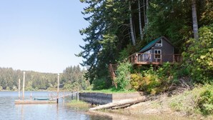 Eine Holzhütte mit einer Veranda, die auf einen See Blick wirft, umgeben von dichtem Wald.