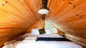 Ein gemütliches Schlafzimmer in einer Holzhütte mit Bett, Kissen und einem Fellüberwurf.