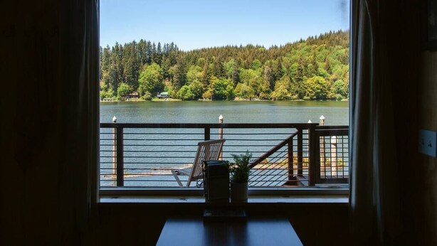 Ein Zimmer mit einem großen Fenster mit Blick auf einen See und einen Wald.