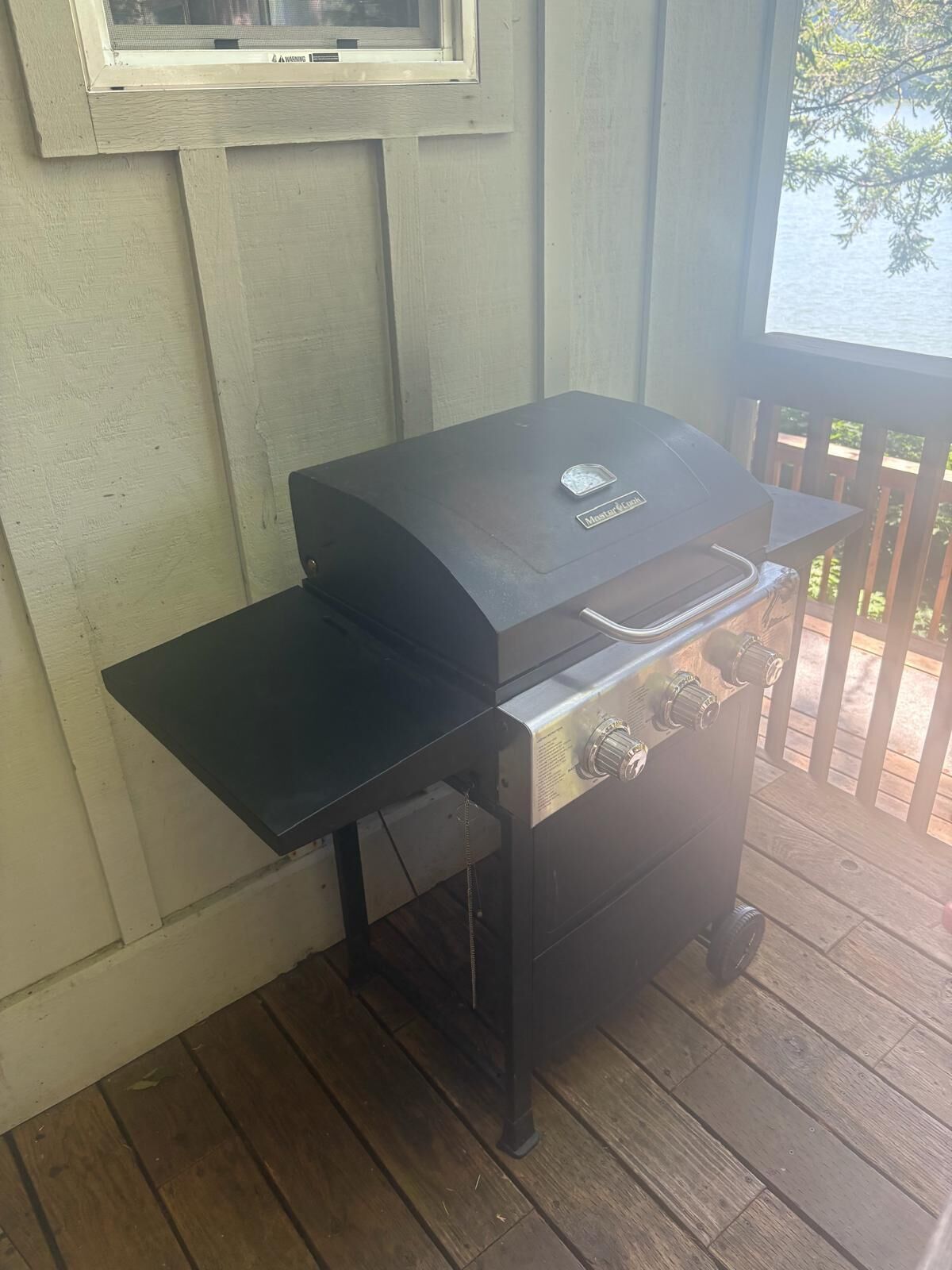 A barbecue grill with a flat top and a side burner, positioned on a wooden deck.