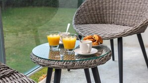 Een glazen tafel met twee glazen jus d'orange, een witte beker en een bord met croissants.