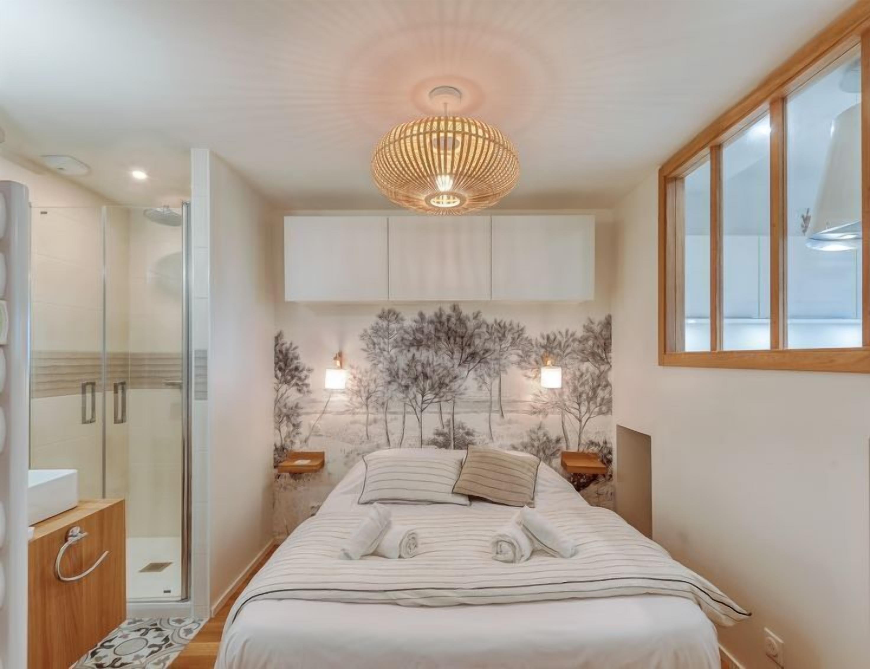 A modern bedroom with a bed, a shower, and a view of the sea.