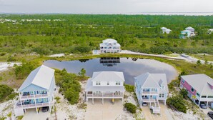 Una propiedad frente a la playa con varias casas, un estanque grande y abundante vegetación.