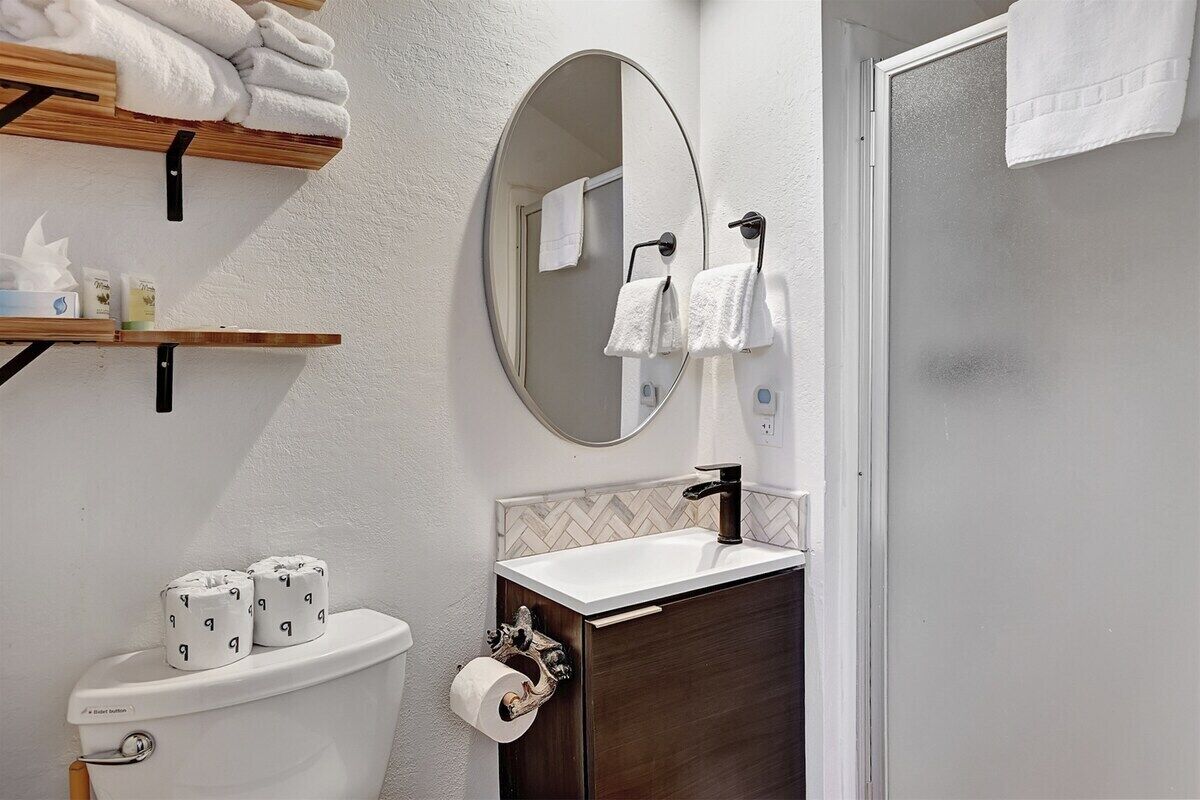 A bathroom with a toilet, sink, mirror, and towel rack.