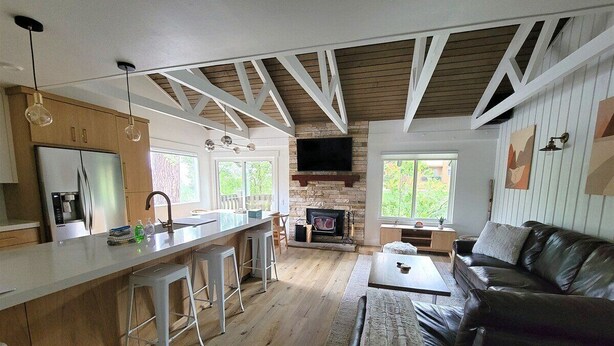 Een moderne keuken met een centraal eiland, een zithoek met een leren zwarte bank en een stenen open haard.