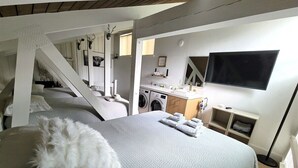 Een slaapkamer met een bed, een wasmachine en een televisie.