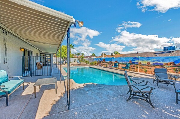 A swimming pool with lounge chairs and a covered patio area.