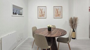 A modern dining room with a round wooden table, four grey chairs, and a vase of flowers. - Apt Porto Ribeira Rio Douro - 6 Guests  (Porto)