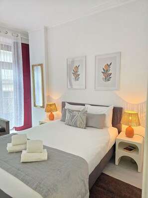 A hotel room with a large bed, two bedside tables with lamps, a mirror, and two framed artworks on the wall. - Apt Porto Ribeira Rio Douro - 6 Guests (Porto)
