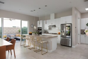 A modern kitchen with white cabinets, stainless steel appliances, and a central island with bar stools.