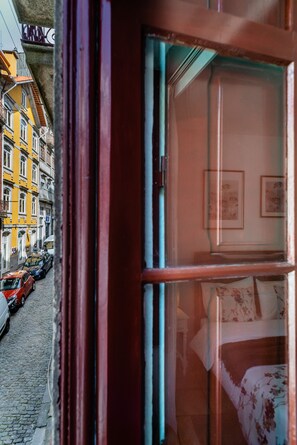 Blick aus dem Fenster auf eine enge Straße mit parkenden Autos und bunten Häusern.