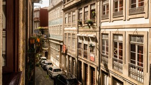 A narrow cobblestone street lined with historic buildings, featuring balconies with plants and a row of parked cars. - Apartment Suite - Rio Douro Ribeira Historic Center  (Porto)