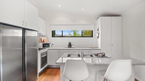 Een moderne keuken met roestvrijstalen apparatuur, een raam met uitzicht en witte kastjes.