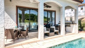 Un espace extérieur aménagé, abrité et doté de meubles en osier, ainsi qu’une piscine.