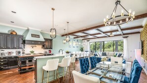 Une cuisine spacieuse avec un coin bar, un plancher en bois et des luminaires modernes.