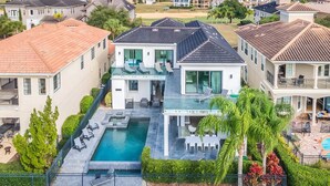 A large, modern house with a swimming pool, multiple balconies, and a well-maintained garden.