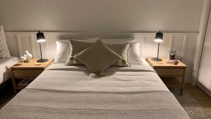 Ein ordentlich eingerichtetes Schlafzimmer mit einem großen Bett, zwei Nachttischen und einem Beistelltisch.