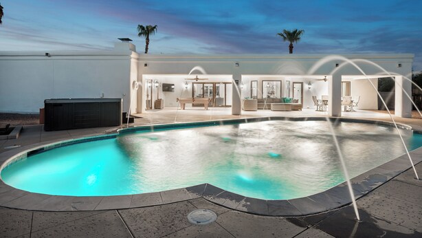 Una casa moderna con piscina, mobiliario de exterior y zona de patio.