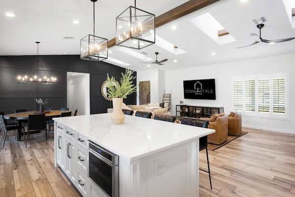 A modern kitchen with a central island, built-in oven, and pendant lighting.