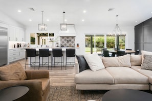 A modern kitchen with white cabinets, a central island with bar stools, and pendant lighting.