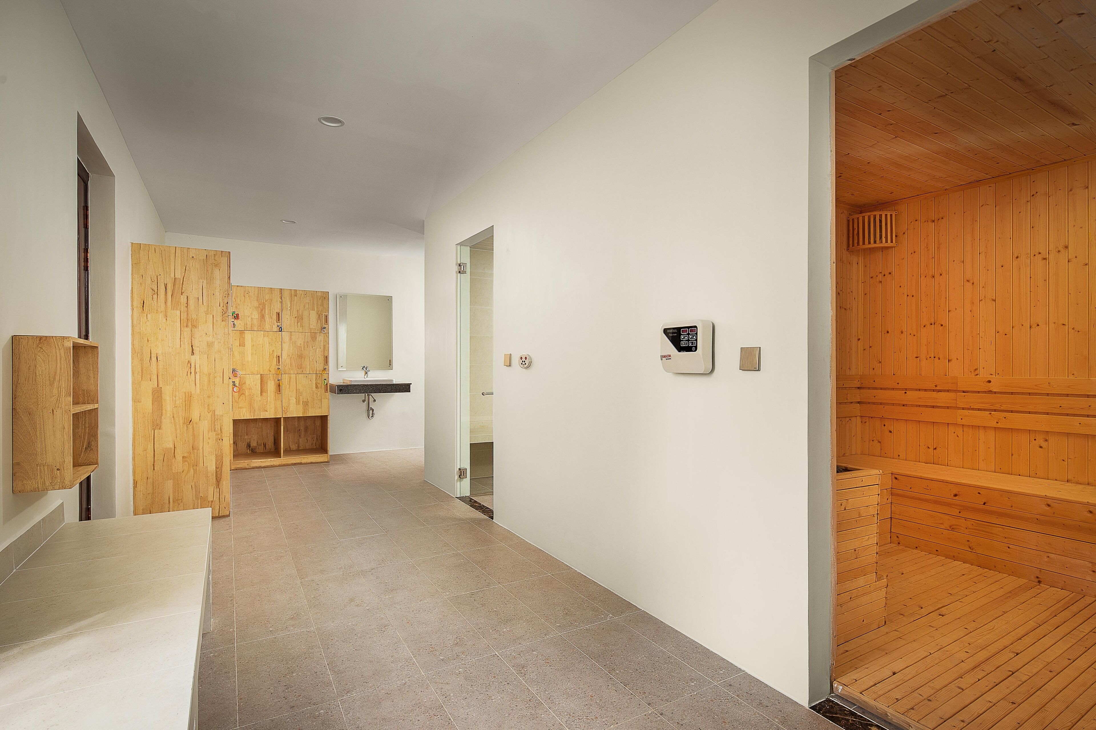 A modern interior with a wooden sauna, a wooden wardrobe, and a bathroom with a sink and mirror.