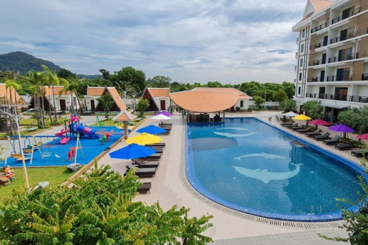 A resort with a large swimming pool, a children's play area, and multiple bungalow-style accommodations.