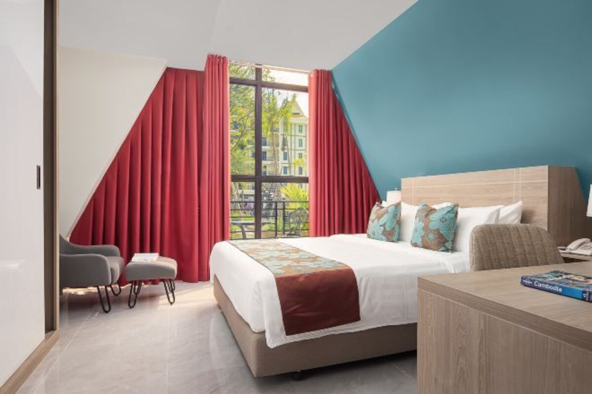 A modern hotel room with a large bed, a desk, and a chair.