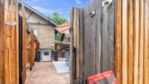 Un étroit sentier mène à un bâtiment à la façade en briques, doté d’une porte en bois et d’une enseigne indiquant « Bienvenue ».