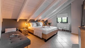 A bedroom with a sloped ceiling, a bed, a bedside table, a chair, and a window. - Gregory's loft (100 meters from the beach) (Αγία Άννα, Εύβοια)