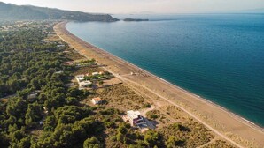 An aerial view of a coastal area with a beach, buildings, and greenery. - Gregory's loft (100 meters from the beach) (Αγία Άννα, Εύβοια)