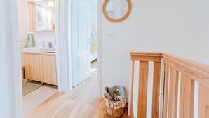 Une salle de bain propre et moderne, avec un meuble-lavabo en bois, un miroir et un panier en osier posé sur le sol.