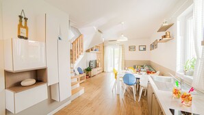 Une cuisine moderne avec des meubles blancs, un plancher en bois et un coin repas comprenant une table et des chaises.