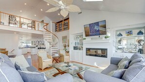 A spacious living area with a modern staircase, a fireplace, and a view of the kitchen. - Shore Elegance | Oceanfront | Private Pool (Virginia Beach)