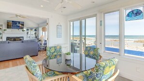 A spacious living area with a large glass door leading to a balcony with a view of the beach. - Shore Elegance | Oceanfront | Private Pool (Virginia Beach)