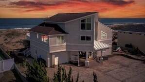 A two-story house with a balcony, located near a beach with a sunset view. - Shore Elegance | Oceanfront | Private Pool (Virginia Beach)