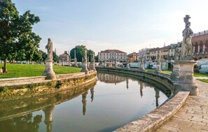 Un bassin paisible agrémenté de statues et offrant un reflet limpide, entouré d’une pelouse bien entretenue et avec des bâtiments en arrière-plan.
