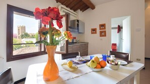 A dining area with a table set for breakfast, a vase with flowers, and a view of a castle through the window. - 2 Bed-Sleeps 6-AirCon-Town Centre-Free Parking (Montagnana)