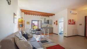 A living room with a sofa, a dining table, and a kitchen area with cabinets and a refrigerator. - 2 Bed-Sleeps 6-AirCon-Town Centre-Free Parking (Montagnana)