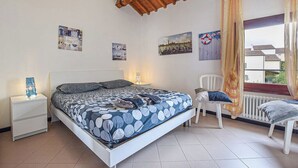 A bedroom with a bed, a nightstand, a chair, and a window with curtains. - 2 Bed-Sleeps 6-AirCon-Town Centre-Free Parking (Montagnana)