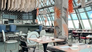 A modern restaurant with high ceilings, bamboo wall decor, and a view of the sky through large windows. - The Studio | Nairobi | 5* Luxury (UN & Two Rivers) (Ruaka, Nairobi)