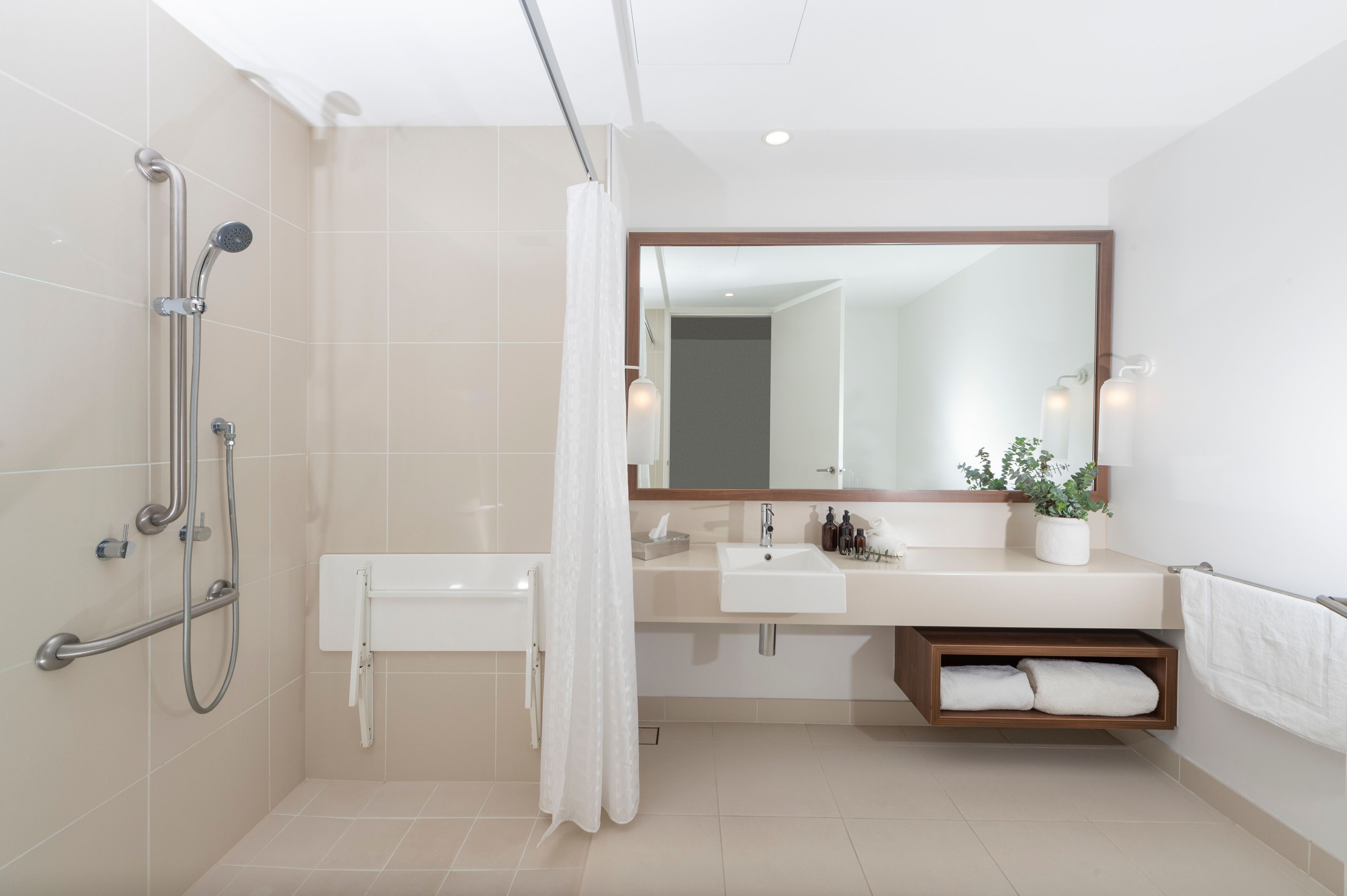 Un baño moderno con ducha, lavamanos, espejo y toallero.