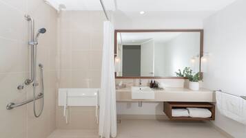 Un baño moderno con ducha, lavamanos, espejo y toallero.
