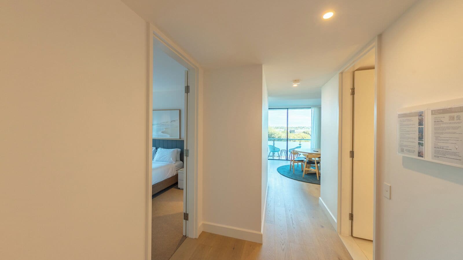 A hallway leading to a bedroom with a large window and a balcony.