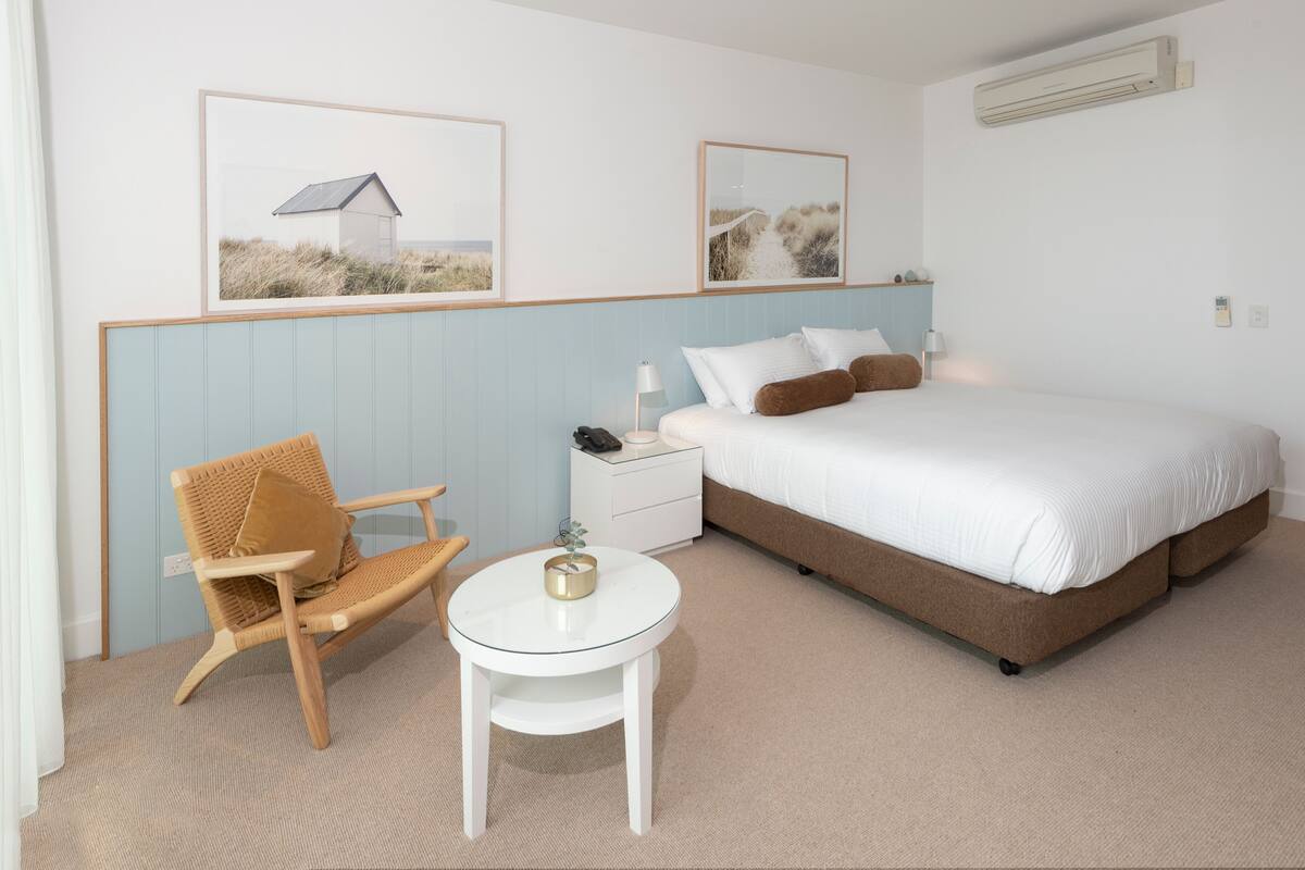 Ein Schlafzimmer mit einem Bett, einem Sessel, einem Nachttisch und einem kleinen runden Tisch.