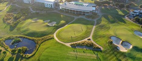 An aerial view of a golf course with bunkers, water hazards, and a clubhouse.